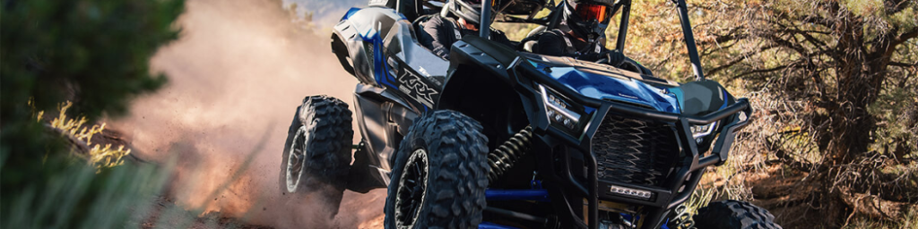 Kawasaki Teryx KRX 1000 kicking up dust while carving through rocky trail with two riders in full gear