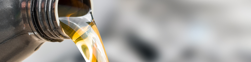 Golden engine oil pouring from bottle during UTV or ATV oil change or engine break-in procedure.