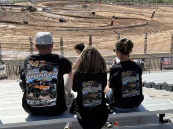 Group of kids sitting at the race track wearing REV6 sponsored t-shirts