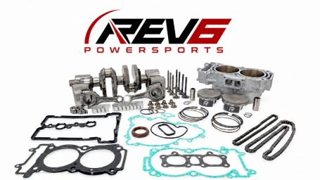 REV6 Powersports logo above engine rebuild kit components, including pistons, cylinders, crankshaft, valves, chains, bearings, gaskets, and seals.